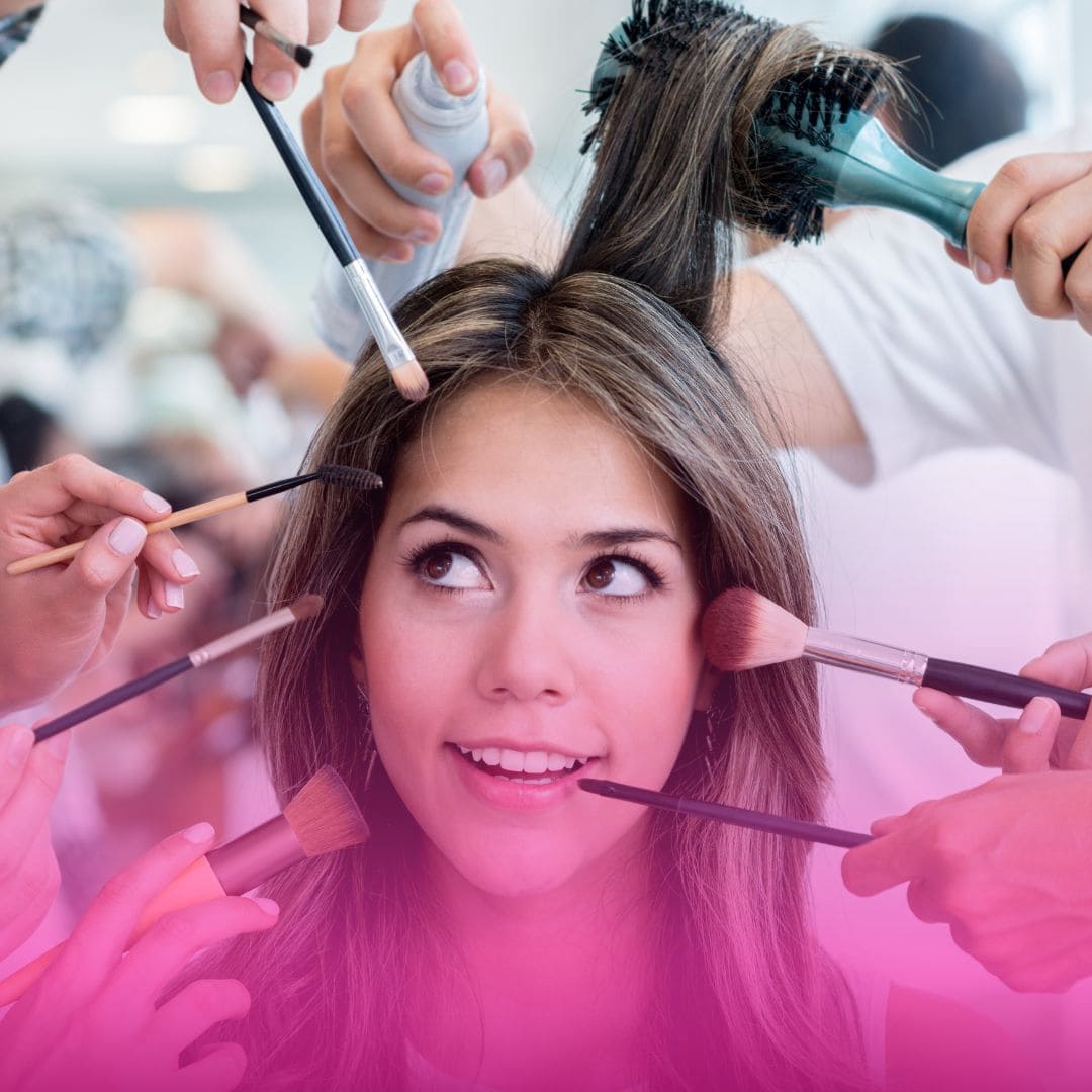 Pretty young woman with brown hair in a beauty salon with multiple hands holding makeup brushes.